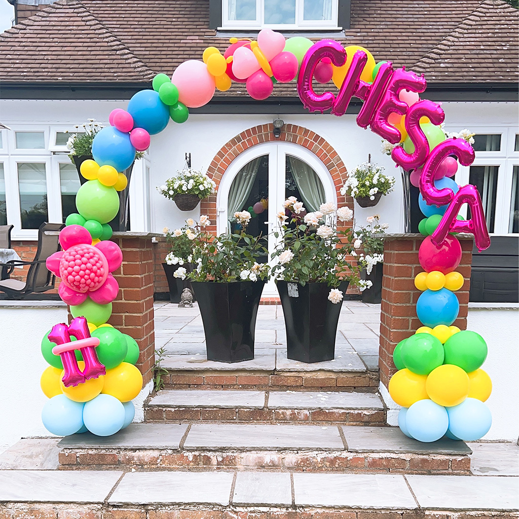 Colourful outdoor balloon arch spelling a child's name over a front door