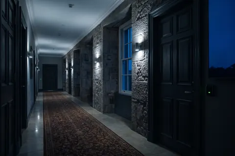 Illustration: a listed-building hotel corridor with thick stone walls, deep window reveals and panelled doors, a lime light glowing on a door's card reader.