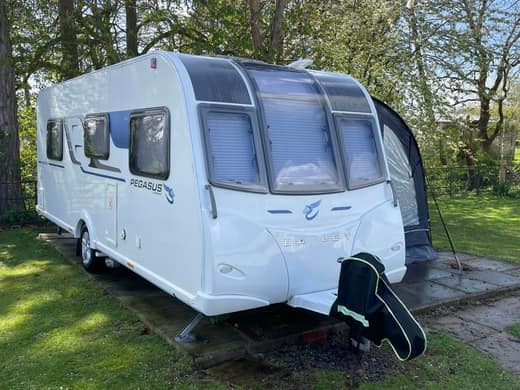 A Bailey Pegasus touring caravan after cleaning, photographed side on with its awning up.