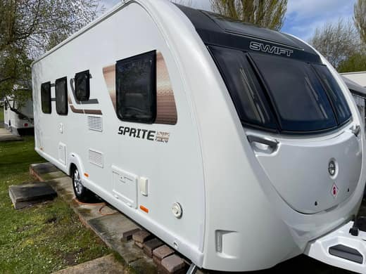 A Swift Sprite touring caravan after cleaning, photographed from the front corner on a grass pitch.
