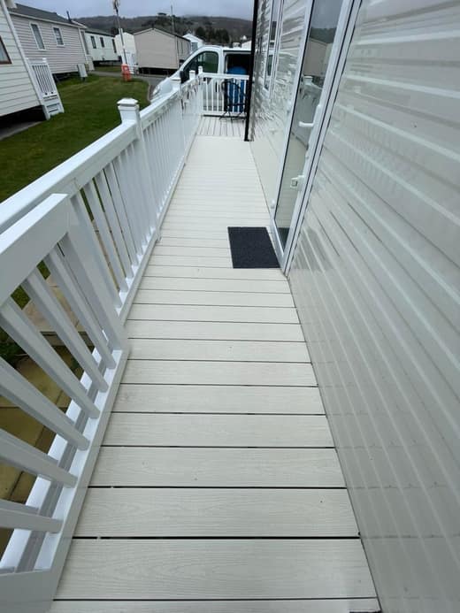 The same decking after cleaning, the boards clean with the white handrail alongside.