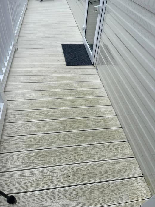 The decking along a static caravan veranda before cleaning, green algae showing in the grain of the boards.