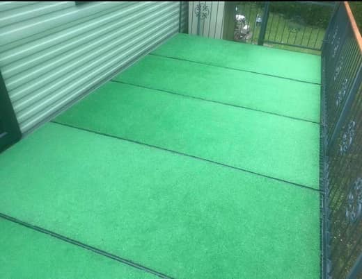 The same static caravan veranda after cleaning, the artificial grass bright green again.