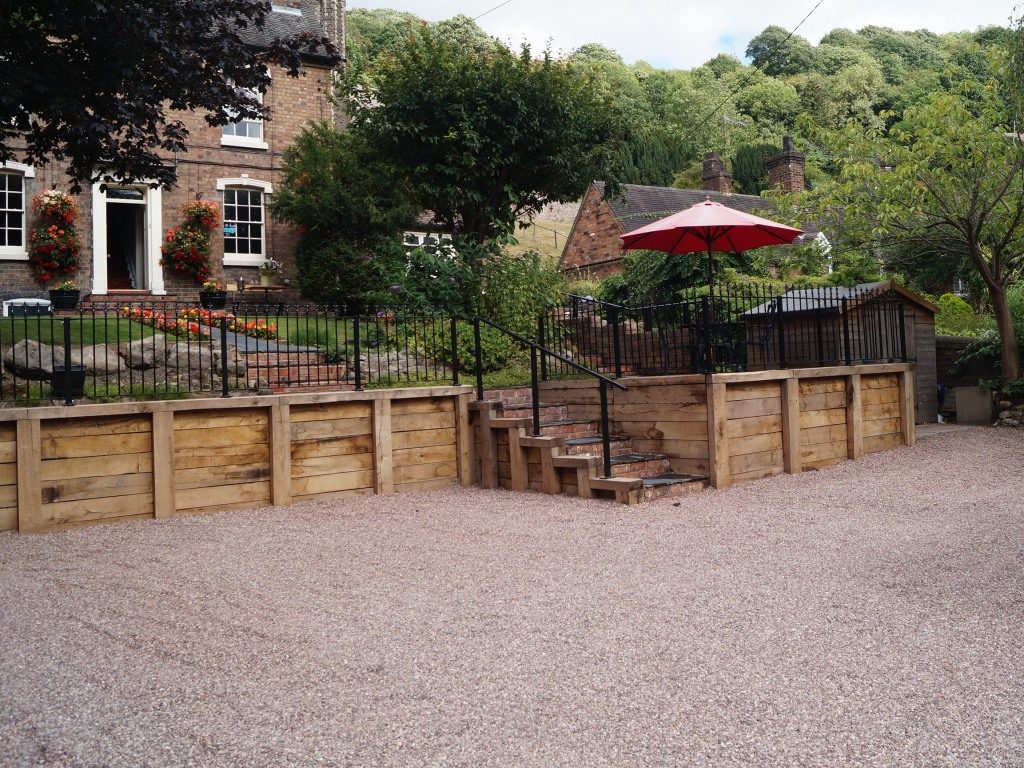 The Foundry Masters House, a detached red-brick Georgian house with flower baskets by the door, set on the wooded hillside of the Ironbridge Gorge