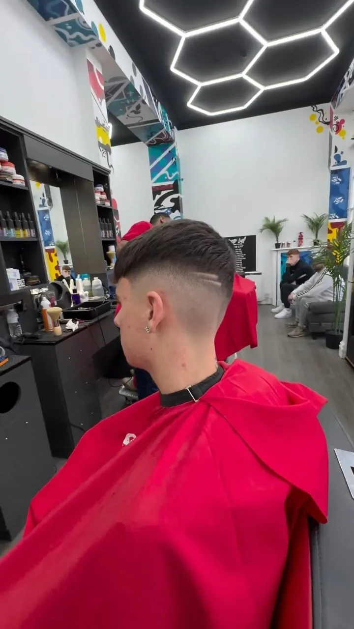 Fresh fade in a red GoodLyf cape mid-appointment