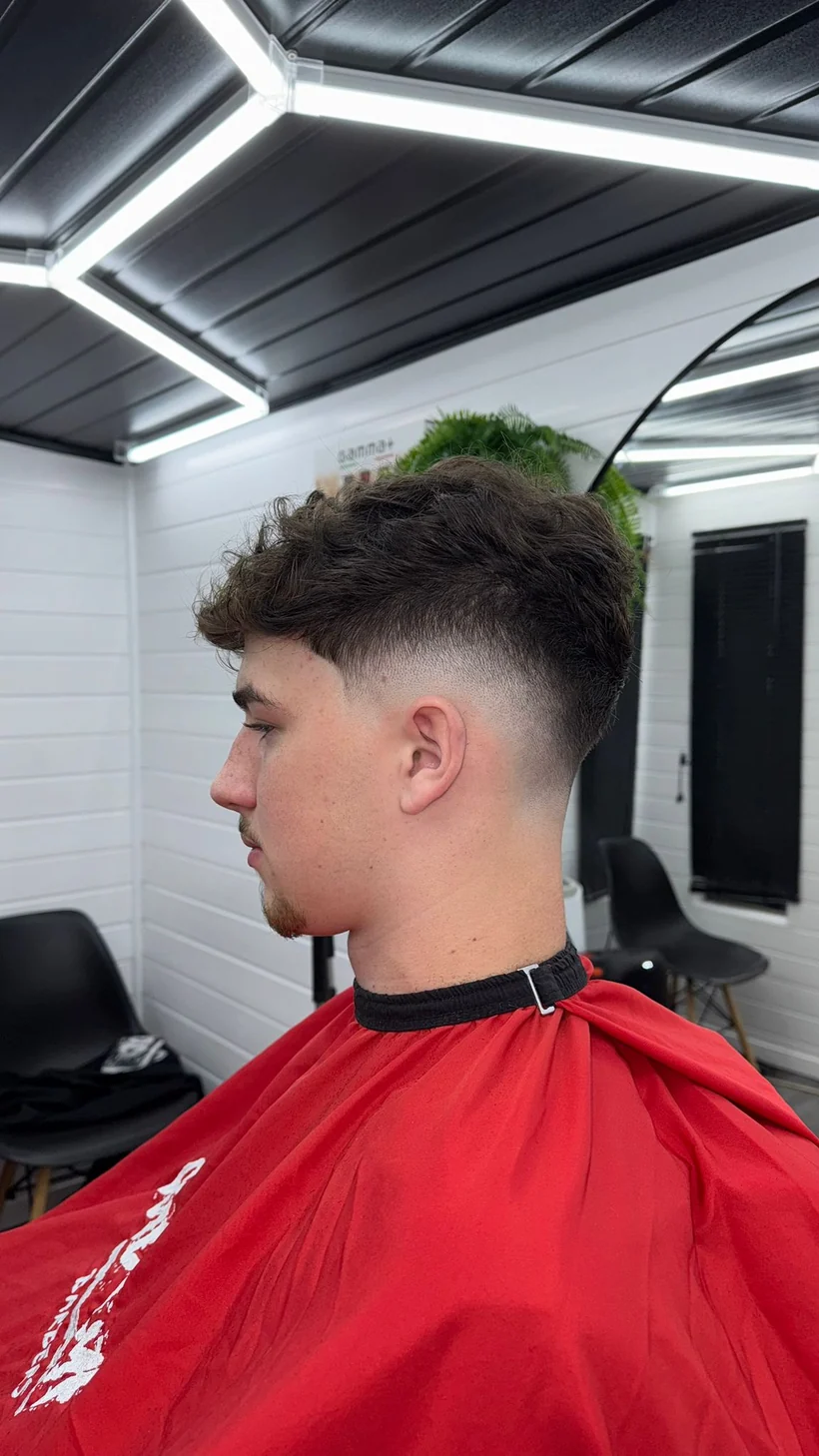 Textured crop with a skin fade, side profile, client in a red cape