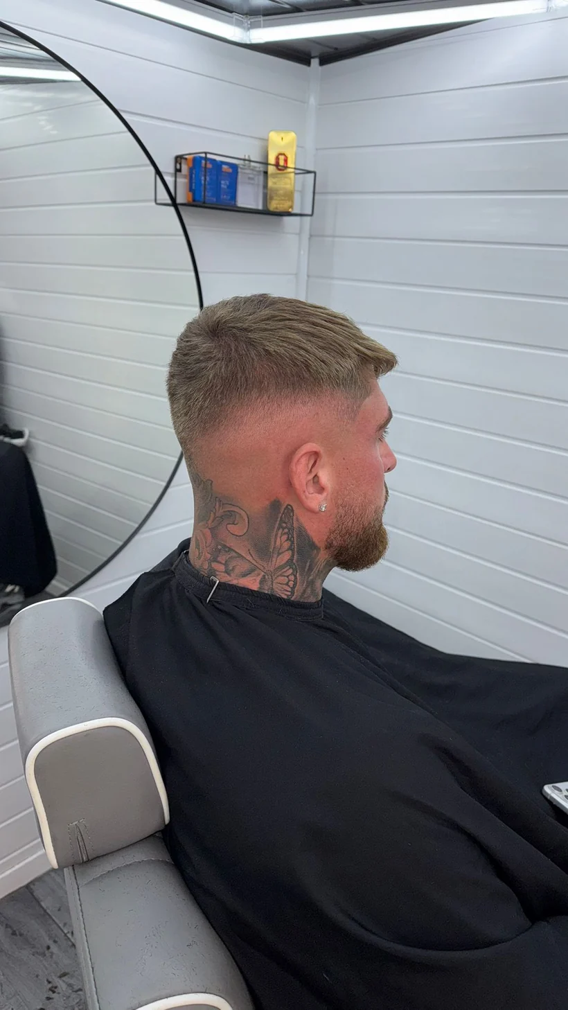 Light textured crop faded into a beard, seen from behind, client in a black cape