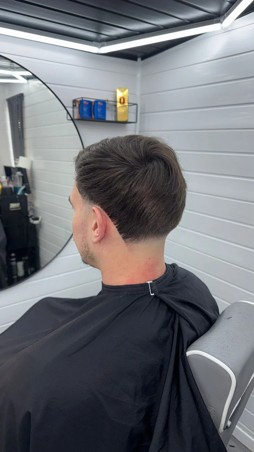 Neat tapered cut with a soft side parting, client in a black cape