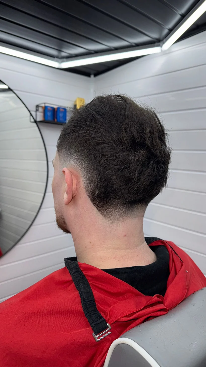 Back view of a textured top tapered into the neckline, client in a red cape