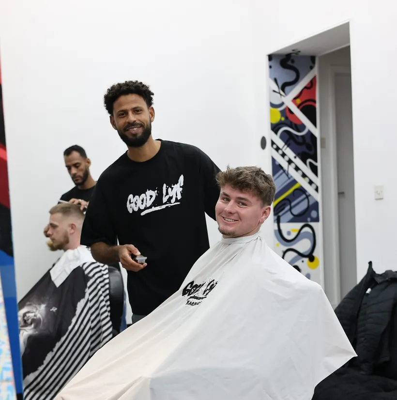 A GoodLyf barber beside a smiling client after a cut