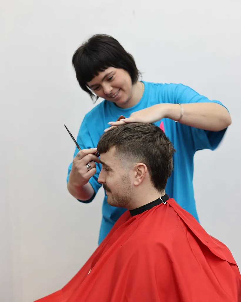 A barber finishing a young client's cut