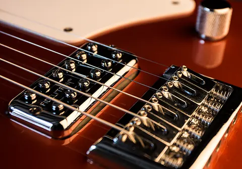 Two humbucking pickups and the chrome bridge saddles of the copper Cabronita, close up