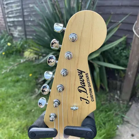 The maple headstock of the gold Stratocaster carrying the J. Davey Custom Guitars script decal