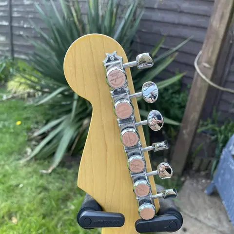The reverse of the gold Stratocaster maple headstock showing the six tuner buttons