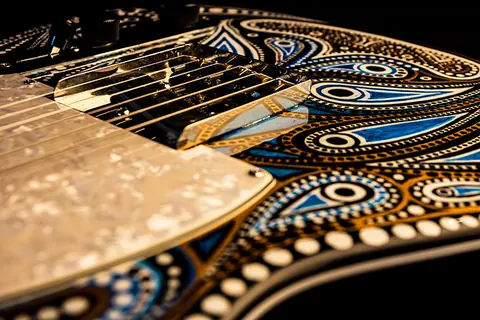 The pearl pickguard against the hand painted body, showing the dotted blue and gold pattern