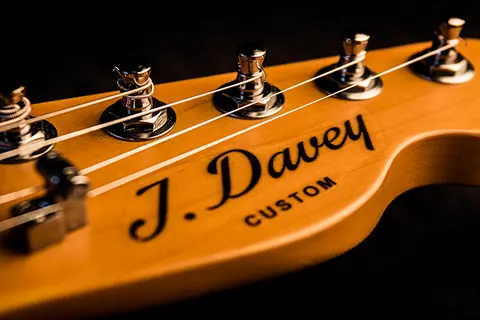 The J. Davey Custom decal close on the maple headstock, strings crossing the nut