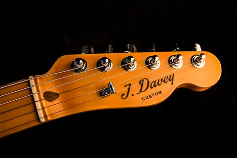 The Cabronita maple headstock carrying the J. Davey Custom script decal, with six chrome tuners