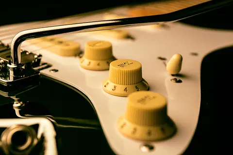 The cream control knobs and tremolo arm of the racing green Stratocaster, close up