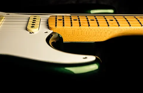 The cutaway of the racing green Stratocaster, pickguard edge, single coil pickup and maple fingerboard