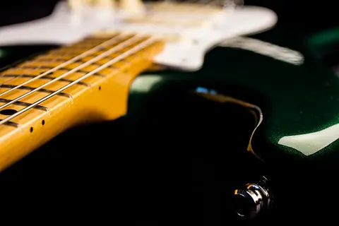 The neck joint of the racing green Stratocaster, maple fingerboard and white pickguard, jack socket behind