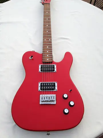 A matte red J. Davey Showroom Series Telecaster shaped guitar with two humbuckers and a single coil, on a white sheet