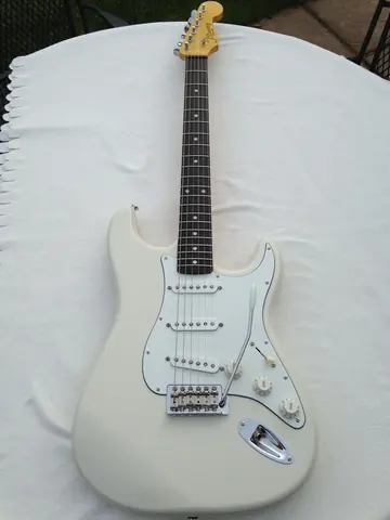 A white J. Davey Signature Series Stratocaster with a rosewood fingerboard, three single coil pickups and a vintage tremolo