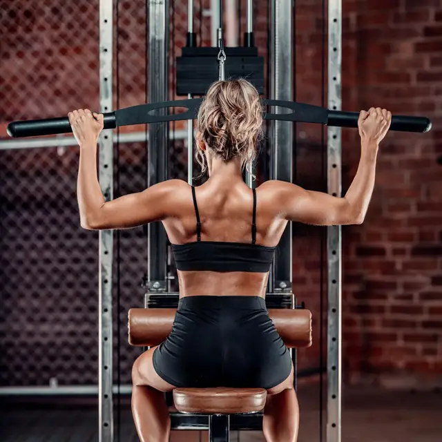 Lucy, seen from behind, doing a lat pulldown in the gym