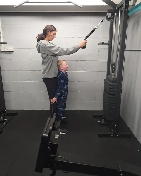 A young boy in a camouflage onesie at his mum's side in the Let Luce studio, looking up at her.