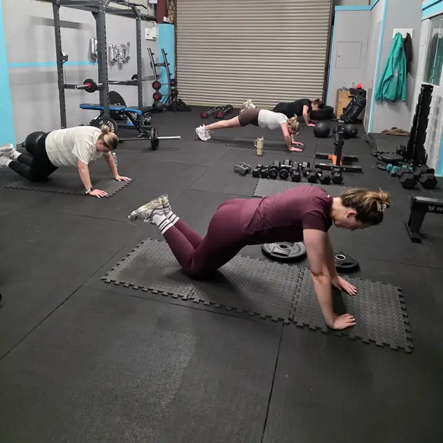 Four women doing floor work on mats at Let Luce, the rig behind them.