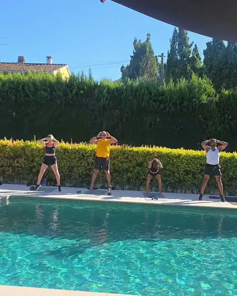 A group doing squats beside the pool.