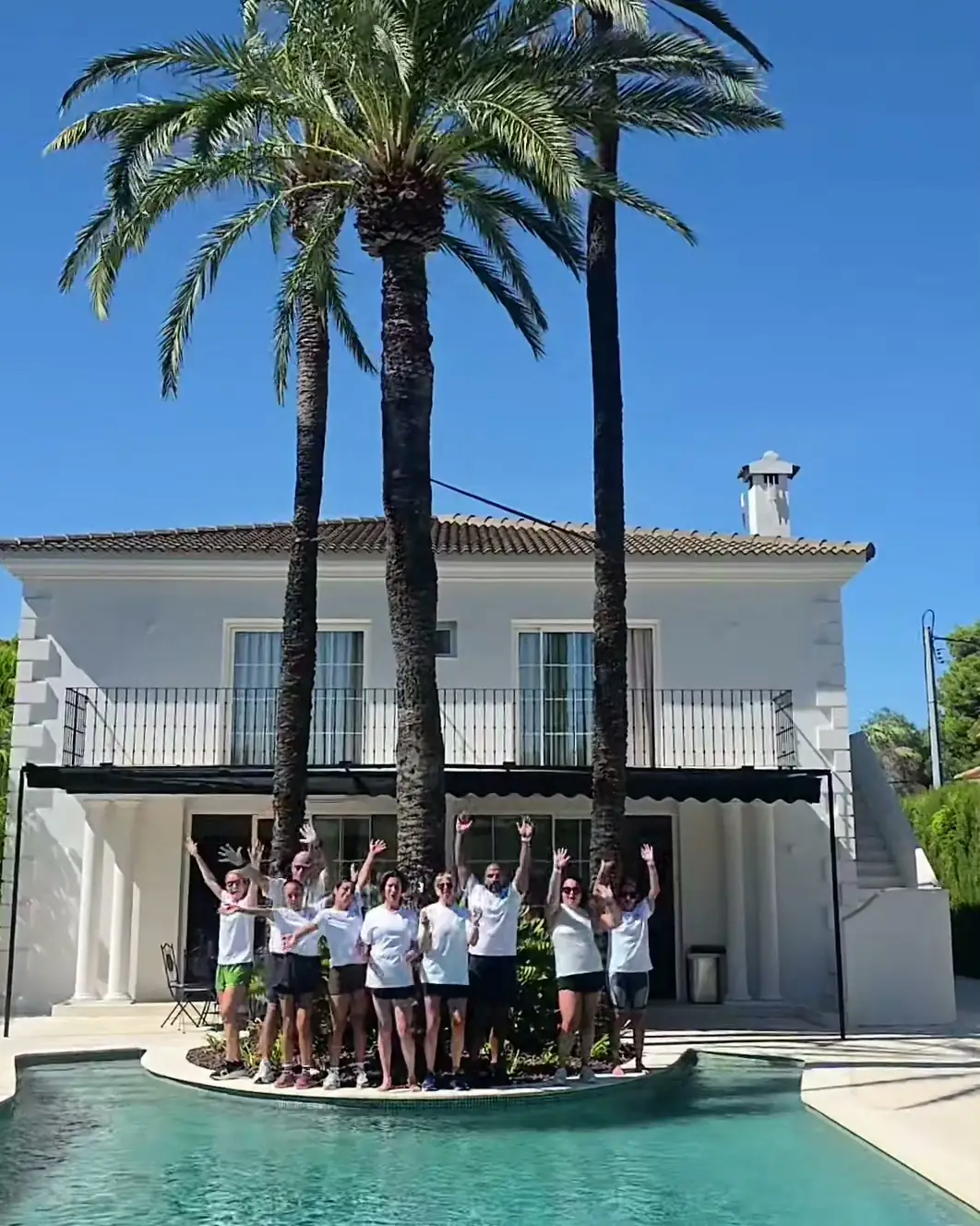 Retreat guests cheering with their arms up on the pool island at the villa in D&eacute;nia.