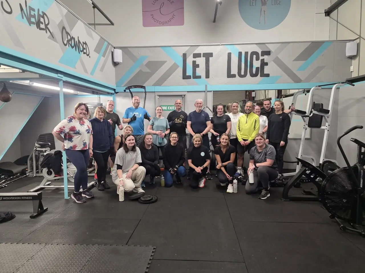 Lucy's crew gathered in the bright blue and grey gym at Unit 49, with LET LUCE painted on the wall behind them.
