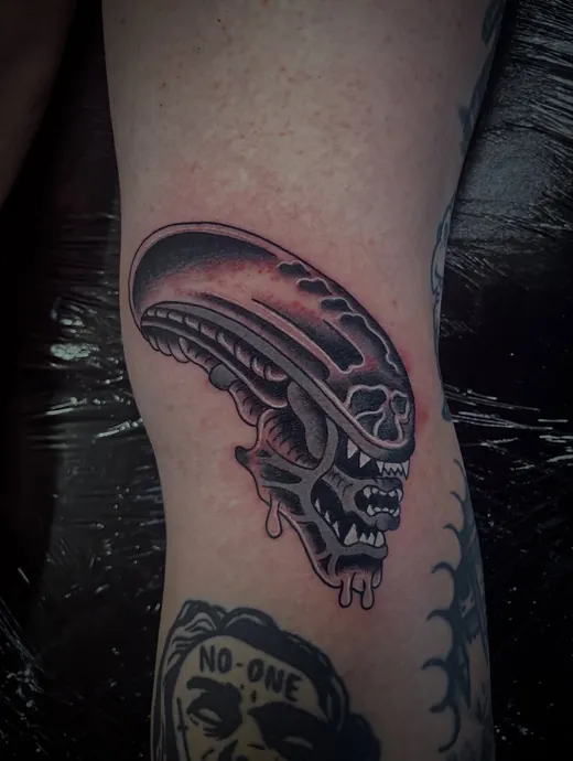 Alien horror piece in black and grey on the lower leg