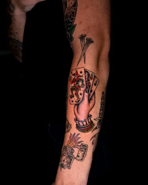 Traditional playing cards, nails and a lighter in colour down the forearm