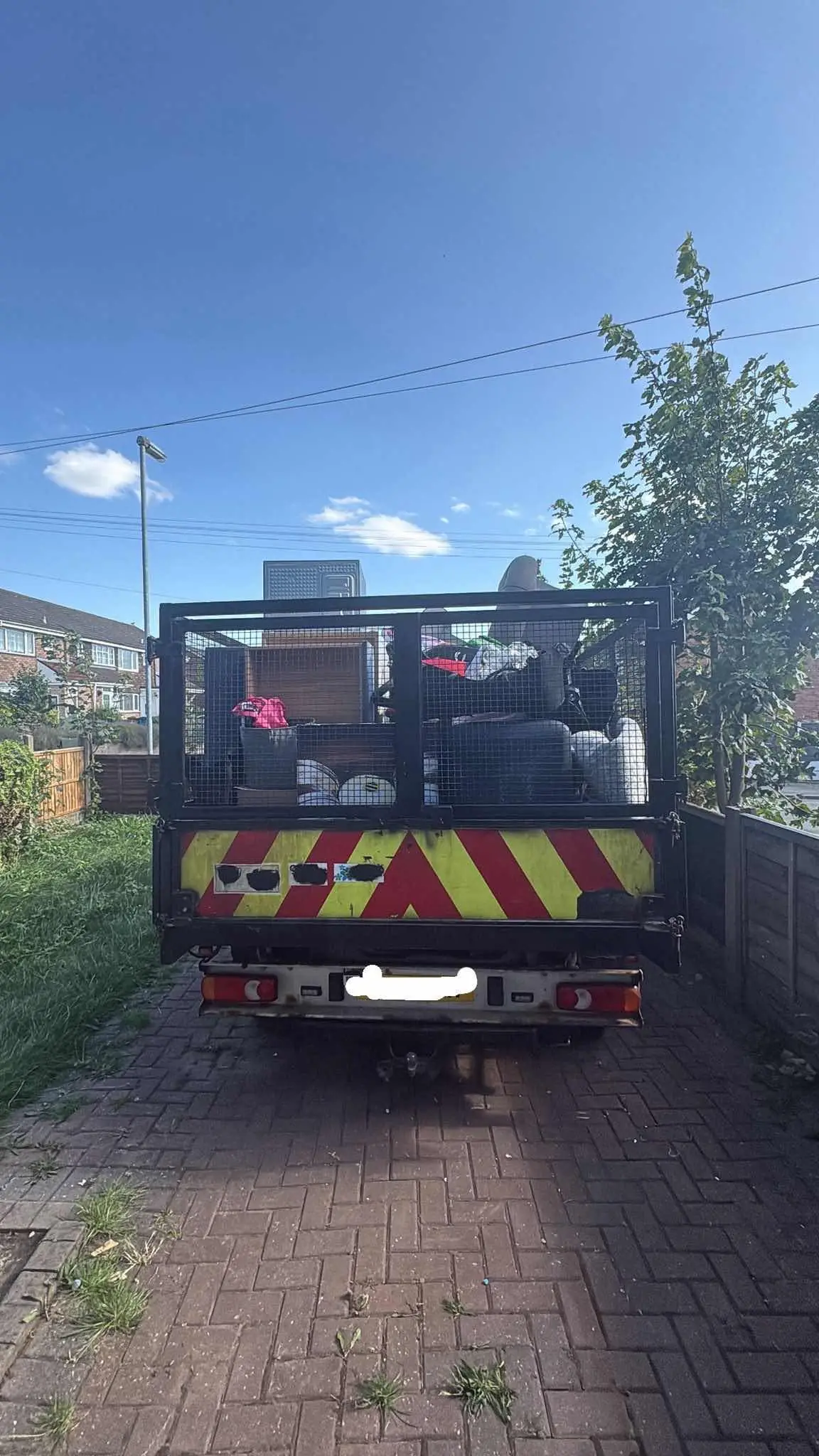 A caged tipper truck fully loaded with old furniture and appliances, ready to be taken away