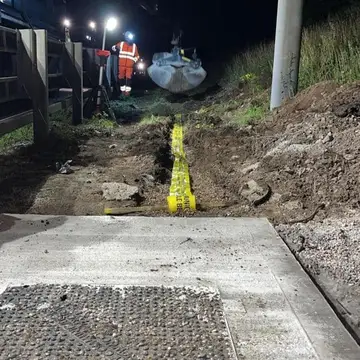 Operative feeding purple ducts into a jointing chamber at night