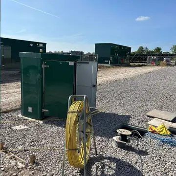 Solar farm substation kiosks and cabling on a compound under blue sky