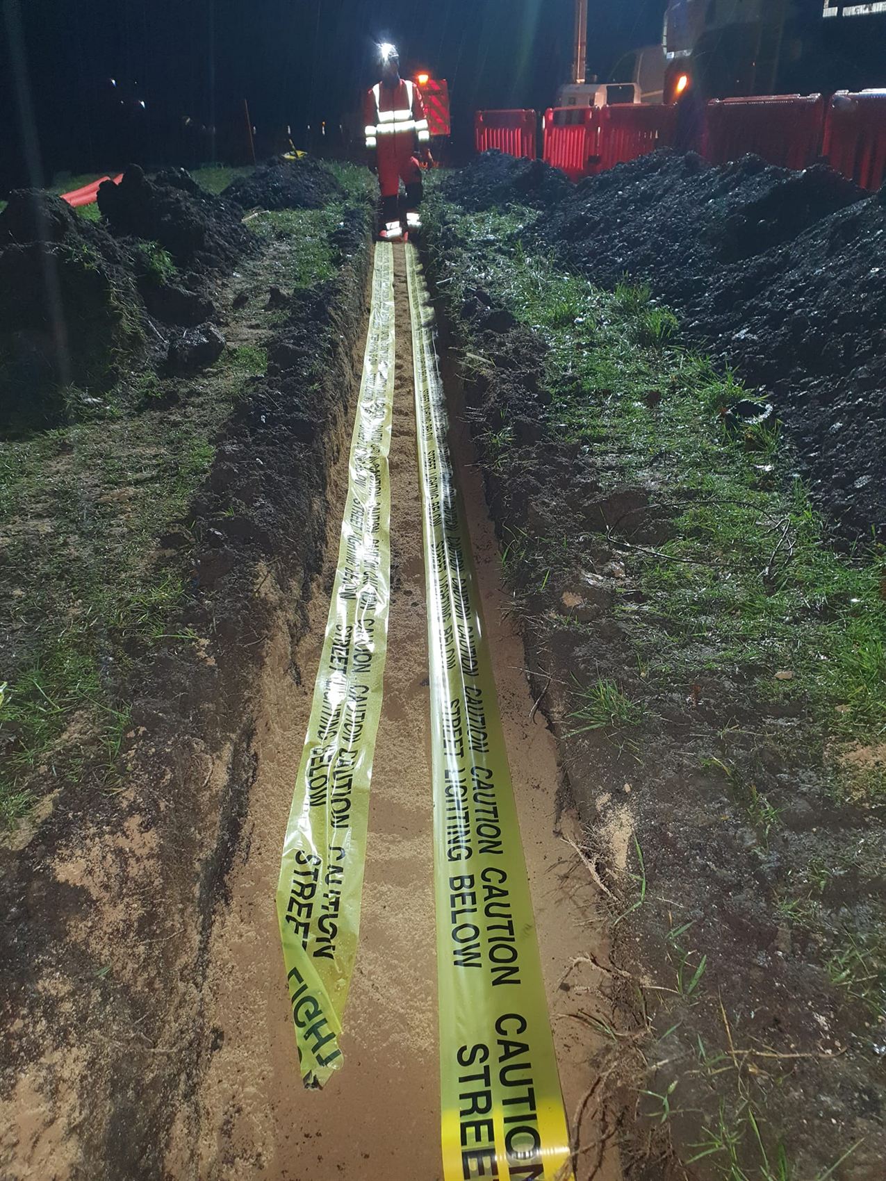 Cable ducting in a trench marked with street lighting warning tape
