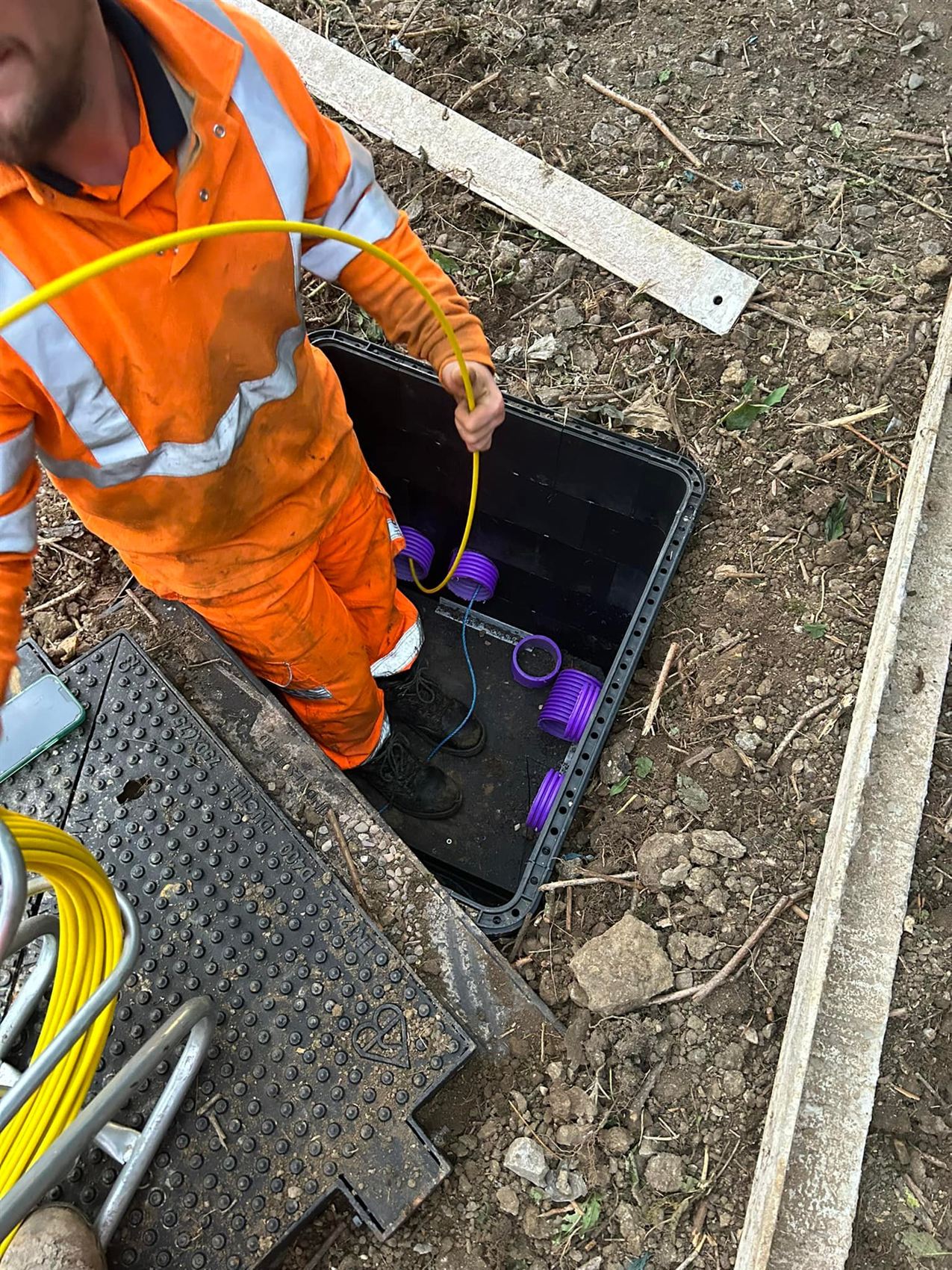 LKP operative in hi-vis feeding fibre optic cable into a jointing chamber on site