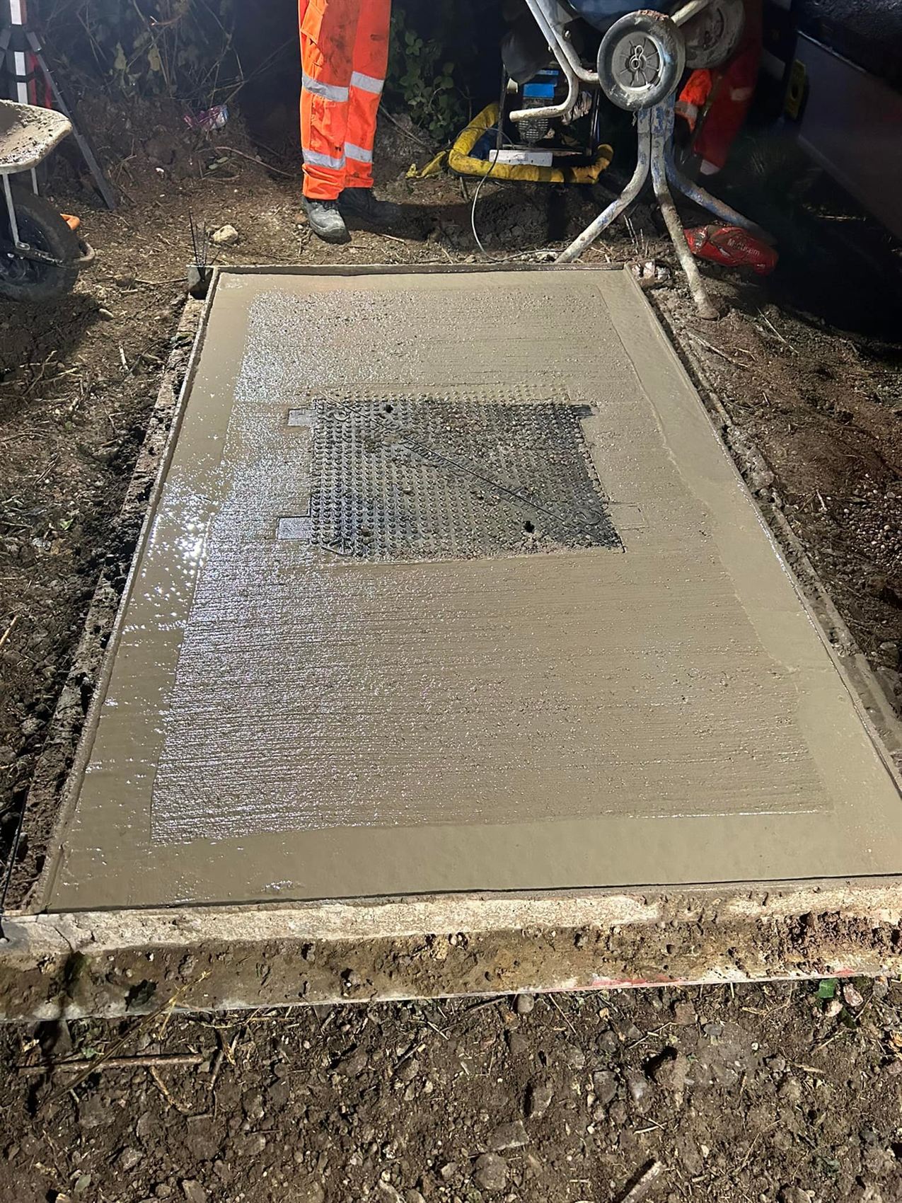Freshly poured concrete surround to a chamber cover at night