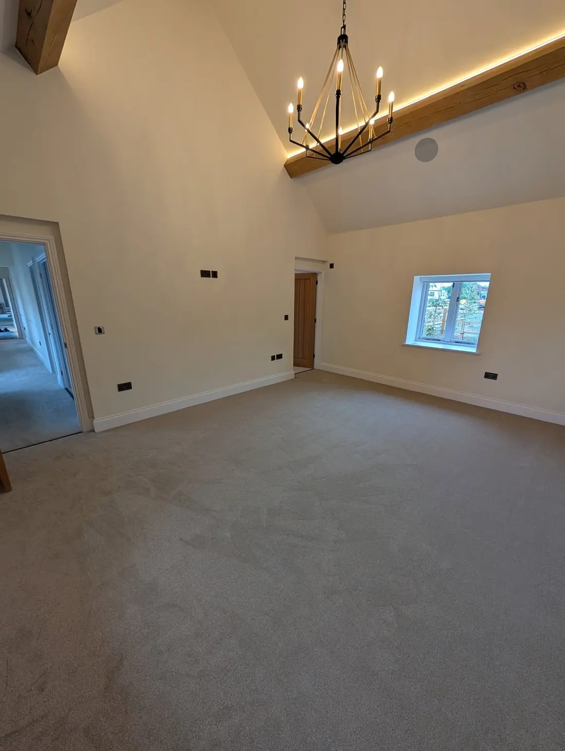 Beige twist carpet fitted wall to wall in a room with a vaulted ceiling and exposed oak trusses.