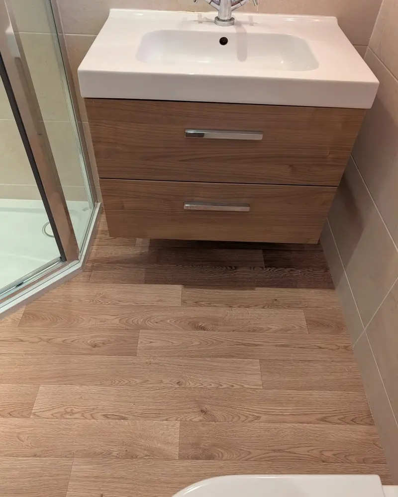 Wood effect flooring running under a wall hung vanity unit with a white basin above it.