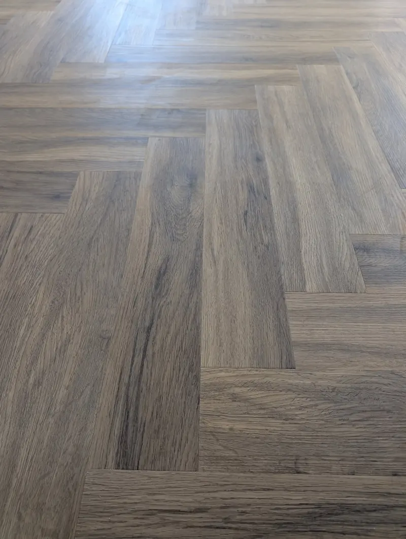Close view of walnut effect herringbone planks meeting in a clean V.