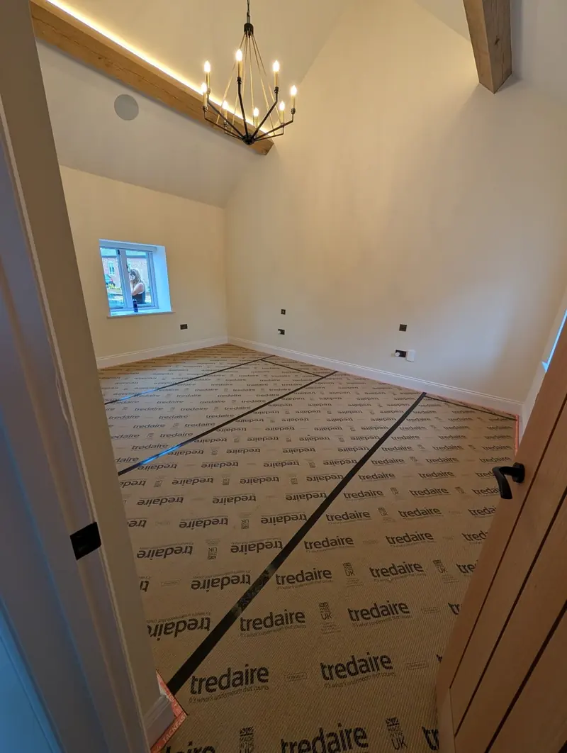Tredaire underlay laid across a landing with black gripper at the edges, under a vaulted ceiling.