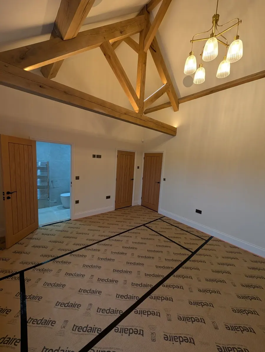 Tredaire underlay taped down across a room with an oak truss and a doorway through to a bathroom.