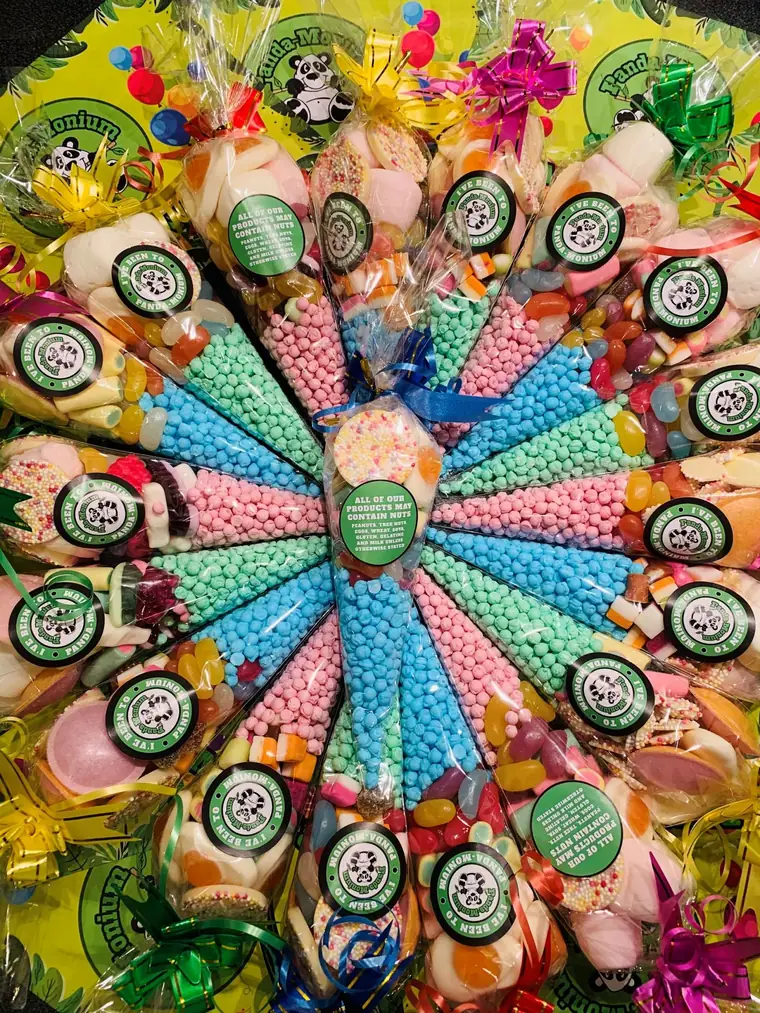 Sweet cones and party bags arranged in a circle, a rainbow of greens, pinks, blues and yellows, each topped with the panda roundel.