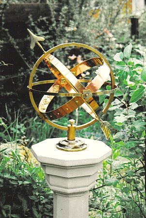 The bi-metal Mandala armillary in copper-bronze and brass, its horizon secured by two Mandala flowers.