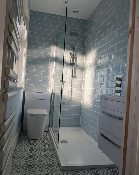 Shower room with blue tiling, a patterned floor and a wall hung drawer unit