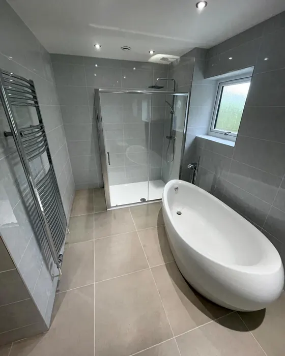 Bathroom with a freestanding oval bath, large grey floor tiles and a walk in shower