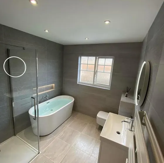 Bathroom with a freestanding bath, glass screen and a large round mirror